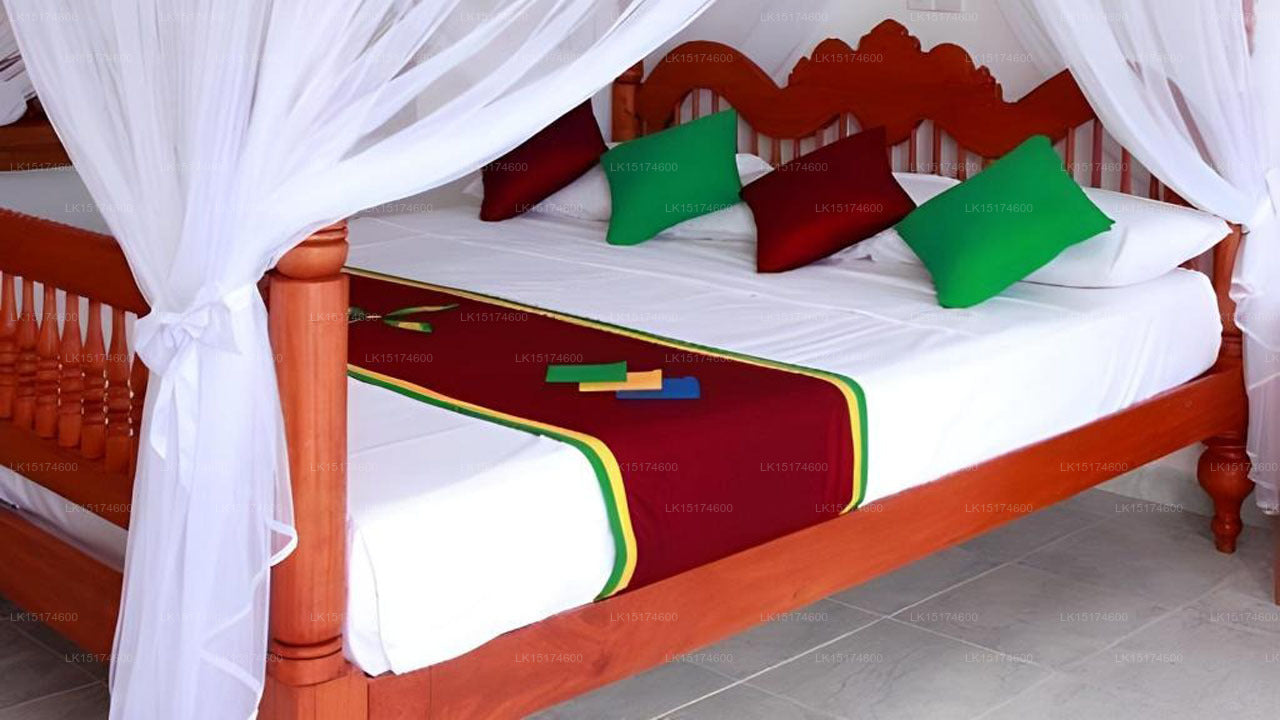 Wooden bed with white bedding, red and green accents, and white curtains.