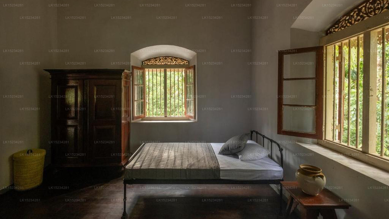 Bedroom with wooden bed, wardrobe, and window with greenery
