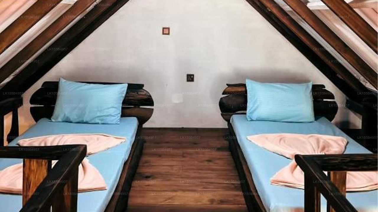 Two single beds with blue bedding and wooden frames in a room with sloped ceiling.